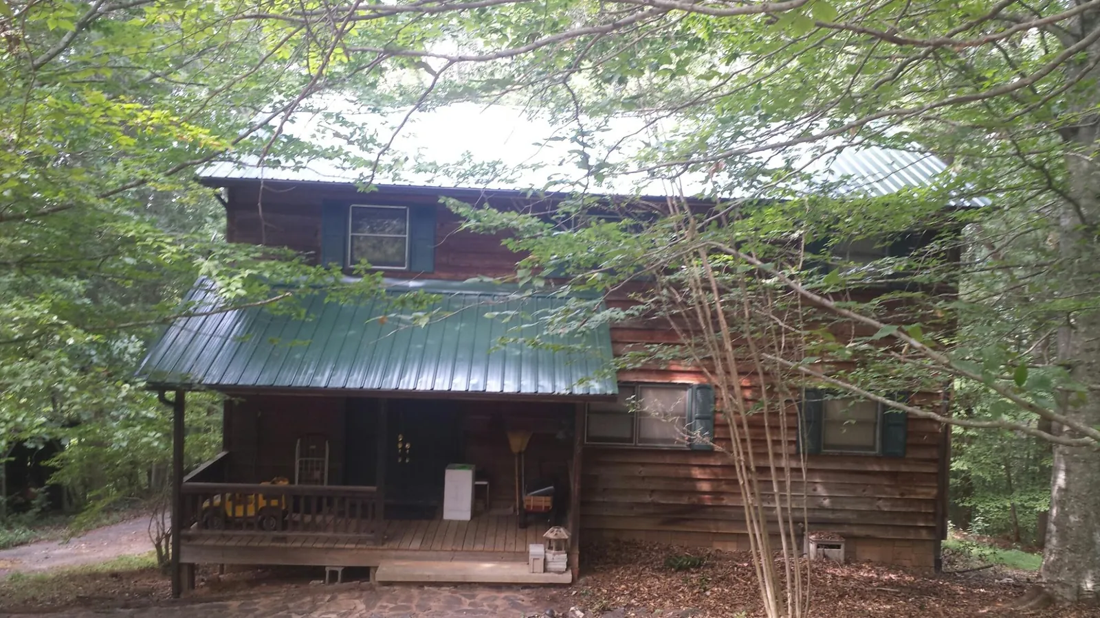 Green metal roof and covered porch on a log cabin in Bloomfield