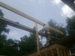 Carpenter setting a ridge beam over a new addition frame — Ice Dam Removal by Roofing Brothers in Bloomfield