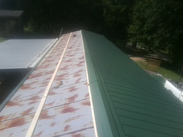 Old rusted panels beside newly installed green metal roofing — Wind Damage Roof Repair by Roofing Brothers in Bloomfield