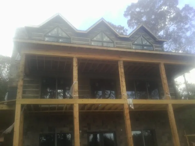 Dormers and porch framing on a large log home under construction — Roof Coating work by our crew in Bloomfield